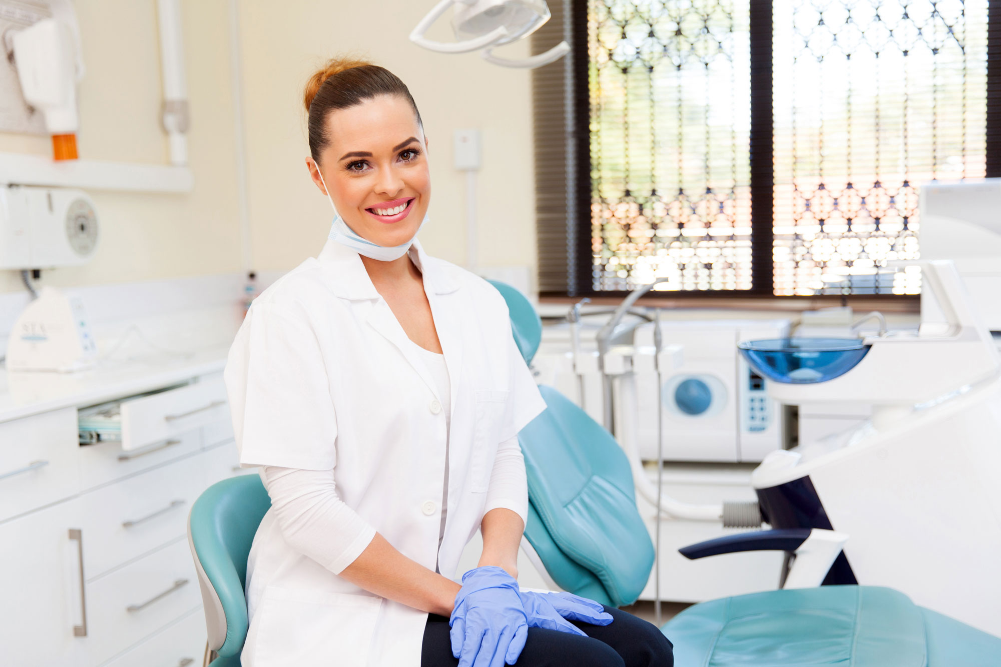 smiling dental provider posing next to dental chair